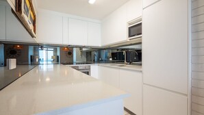 Una cocina moderna con una isla grande, electrodomésticos integrados y vistas al área de estar.