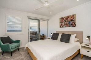 A bedroom with a large bed, a ceiling fan, a sliding glass door to a balcony, and a painting on the wall. - Seadrift 31 on Browning Street (Byron Shire)
