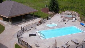 A swimming pool with a hot tub, lounge chairs, and a covered area with a roof. - I'll Be Back Ski in/out condo (bellaire)