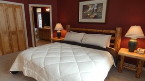 A bedroom with a large bed, wooden headboard, two bedside tables with lamps, a framed picture on the wall, and a wooden wardrobe. - I'll Be Back Ski in/out condo (bellaire)