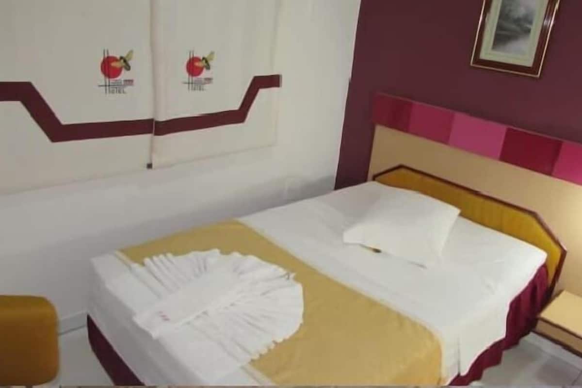 A hotel room with a bed, a nightstand, and a chair.