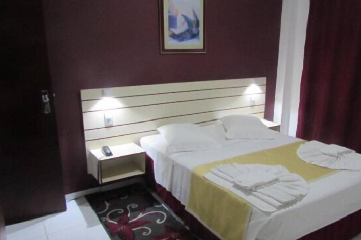 A hotel room with a bed, bedside table, and a nightstand.