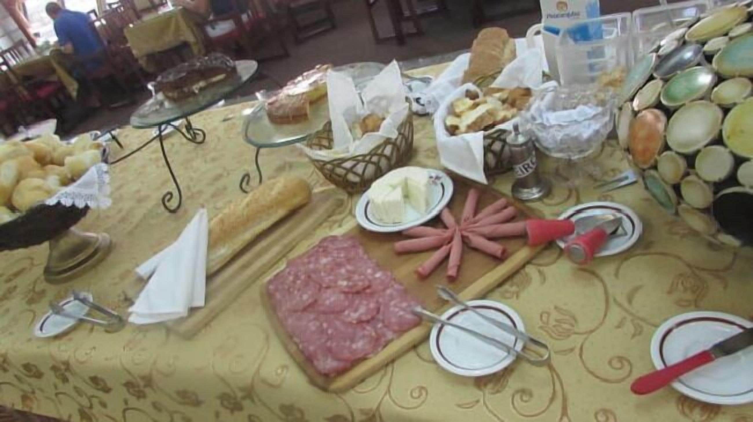 Una mesa de buffet con diversos alimentos, incluyendo pan, queso y embutidos.