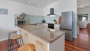 Una cocina moderna con una isla central, electrodomésticos de acero inoxidable y vista al área de estar.