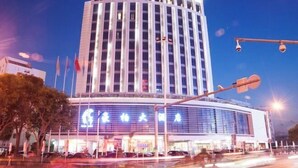 Ein mehrstöckiges Hotel mit modernem Design, das durch einen markanten Eingangsbereich mit beleuchteter Beschilderung besticht.