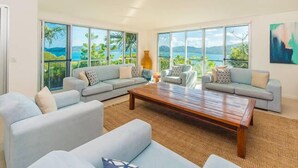 A spacious living room with a large wooden coffee table, two grey sofas, and a ceiling fan.