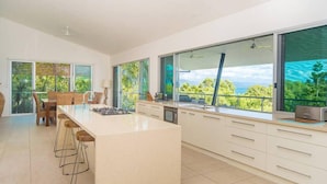 A modern kitchen with a large island, ample natural light, and a view of greenery.