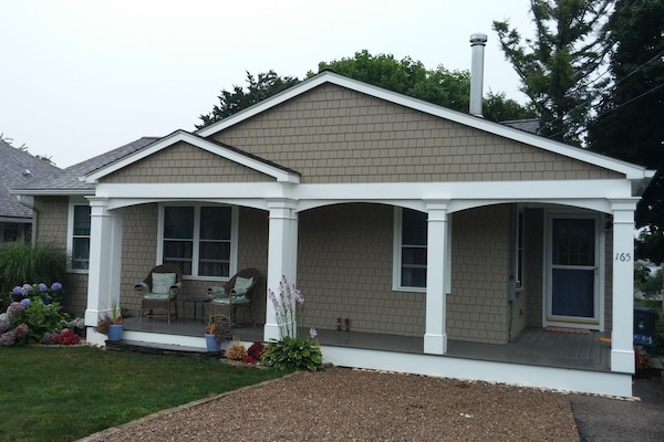 Front of house with porch and chairs for relaxing. Beautiful flowers in season.