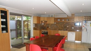 A modern kitchen with a wooden table and red chairs, a built-in oven, and a refrigerator.