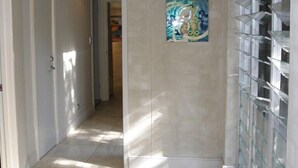 A hallway with a tiled floor, a door on the left, and a glass display case on the right.