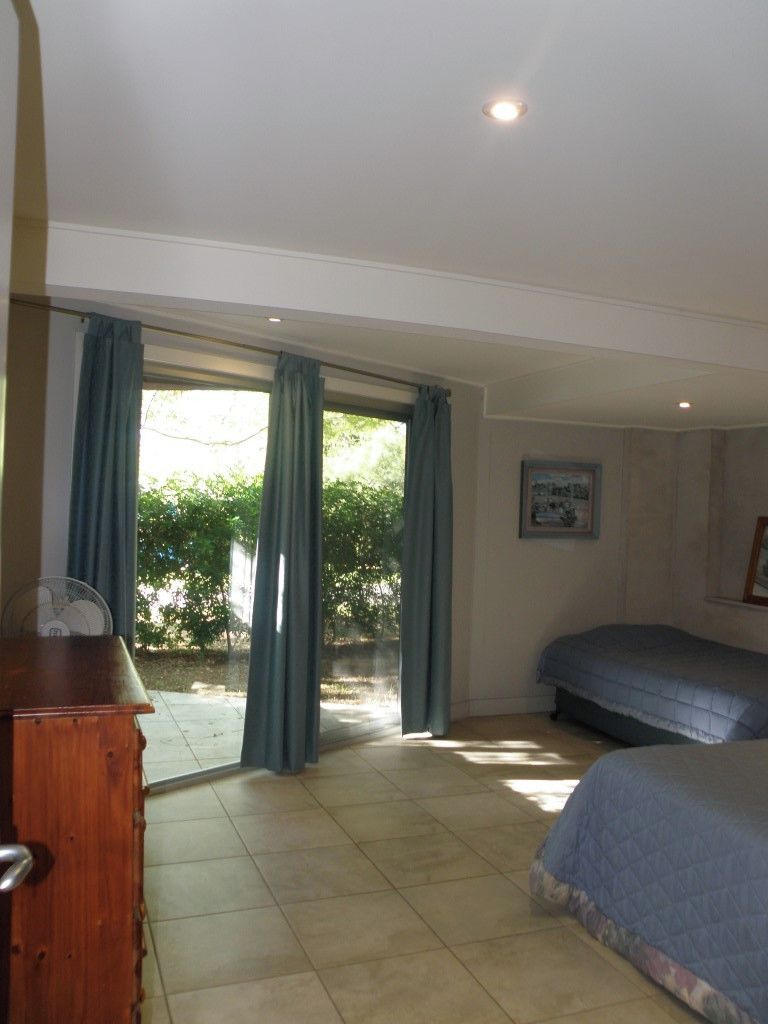 A bedroom with a bed, a dresser, and a sliding glass door leading to an outdoor area.