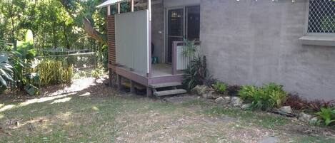 A small, single-story house with a porch, a covered outdoor area, and a concrete wall.