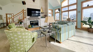 Un salon spacieux doté d’une cheminée, d’un téléviseur et d’une grande fenêtre donnant sur la mer.