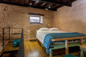 A rustic room with a wooden bed, a small window, and a wooden bench. - History and Charm in Old Town Chania (Chania)