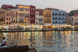 A waterfront hotel with multiple stories, balconies, and a bustling street scene in the background. - History and Charm in Old Town Chania (Chania)