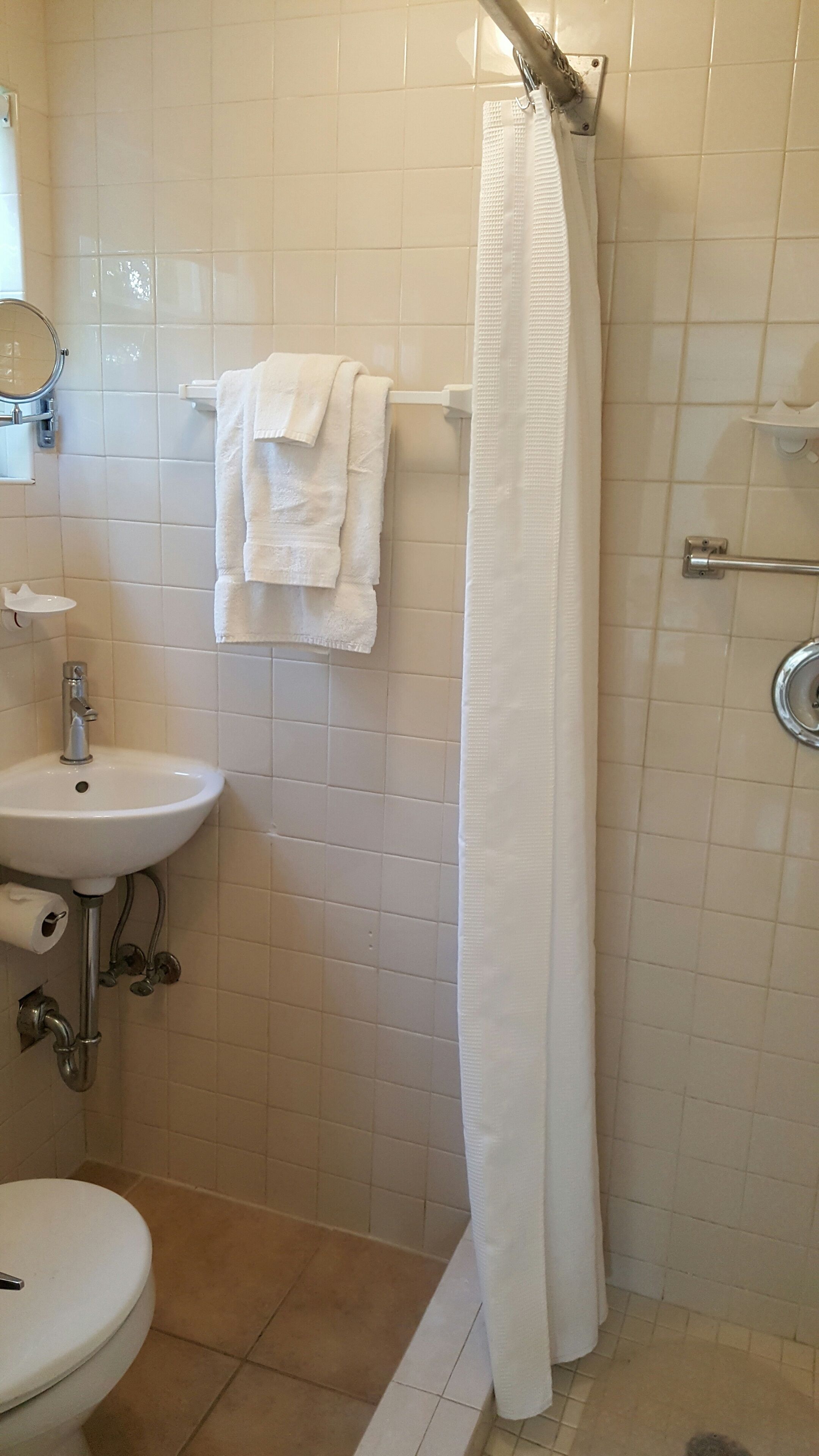 A bathroom with a white sink, toilet, and shower curtain.
