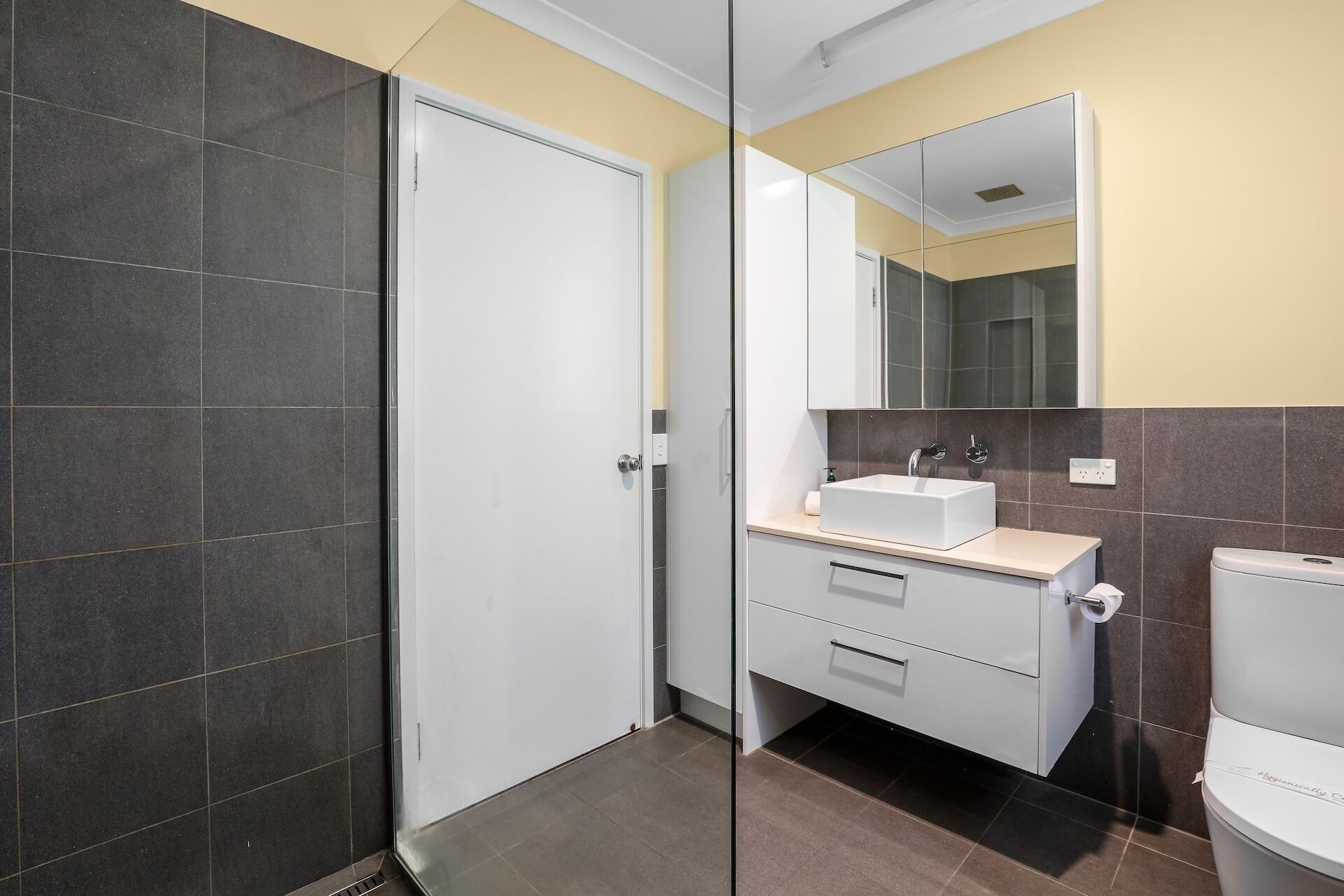 A modern bathroom with a glass shower enclosure, a white sink, and a toilet.