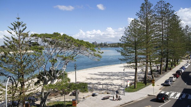 A beachside view with a paved walkway, benches, and a parking area. - Lowanna Unit 10, 24 Bulcock Beach Esplanade, Bulcock Beach (CALOUNDRA)