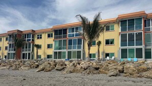 A beachfront hotel with multiple floors, large windows, and a rocky shoreline. - Siesta Key - Gulf-Front Retreat - 2 BR – Free Boat Docks - Upscale (Sarasota)