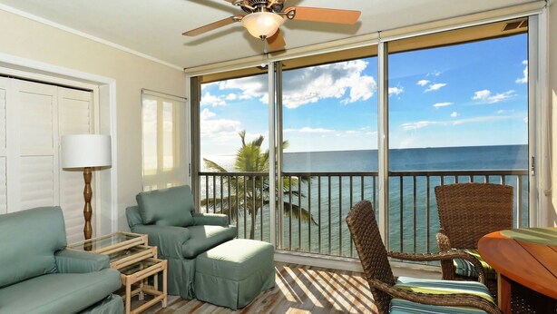 A balcony with a view of the ocean, furnished with a sofa, chairs, and a table. - Siesta Key - Gulf-Front Retreat - 2 BR – Free Boat Docks - Upscale (Sarasota)