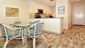 A modern kitchen with white cabinets, a glass dining table, and wicker chairs. - Siesta Key - Gulf-Front Retreat - 2 BR – Free Boat Docks - Upscale (Sarasota)