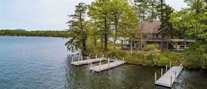 A lakeside cabin with dock access, surrounded by trees and a mountain in the background.