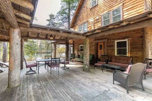 A wooden cabin with a covered patio area featuring outdoor furniture. - Unique Post & Beam Cabin on Winnipesaukee-  Mark Island-Gilford, NH (Gilford)