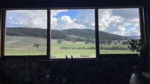 A kitchen with a large window overlooking a rural landscape. - Langbrook Estate Cottage (Yarra Junction)