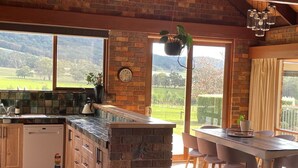 A kitchen with a brick wall, a window, a sink, and a refrigerator. - Langbrook Estate Cottage (Yarra Junction)