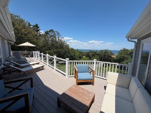 Une terrasse dotée de mobilier d’extérieur, d’une rambarde blanche et offrant une vue sur l’océan.