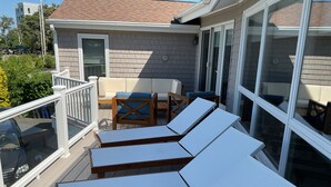 Una terrazza con poltrona relax bianche e un tavolo di legno con cuscini blu.