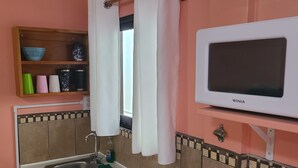 Une cuisine équipée d’un évier, d’une cuisinière, d’un four à micro-ondes et d’une étagère contenant des ustensiles de cuisine.