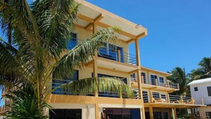 Un hôtel à plusieurs étages doté de balcons, d’une piscine et d’un aménagement paysager de style tropical.