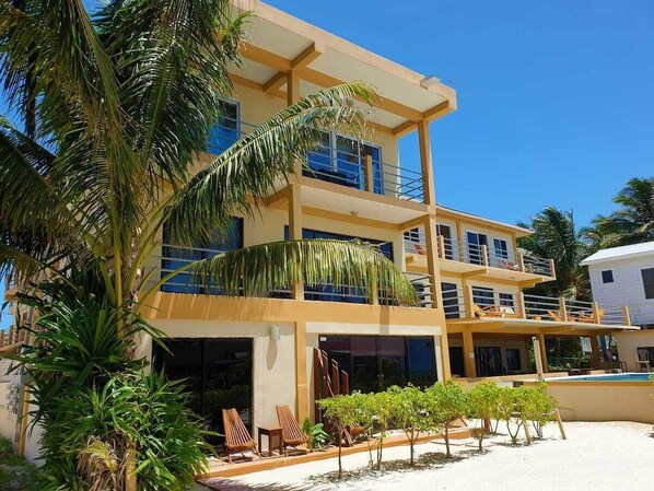 A multi-story hotel with balconies, a pool, and tropical landscaping.
