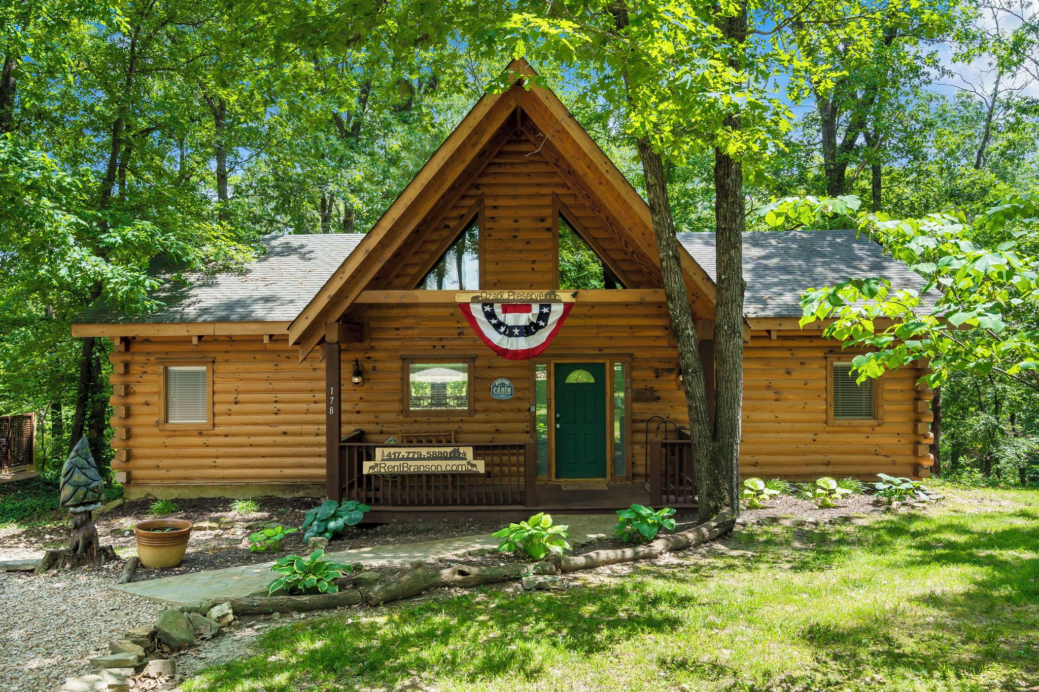 A log cabin with a green door, a small window, and a sign above the door.