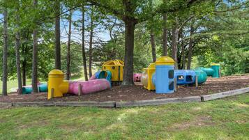 A playground with colorful slides and play structures surrounded by trees.