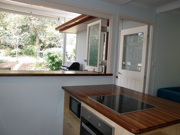 Una cocina con encimera de madera, horno empotrado y ventana con vistas a un jardín.