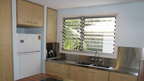 Een moderne keuken met houten kastjes, een ingebouwde kookplaat, een roestvrijstalen spoelbak en een raam met zonwering.