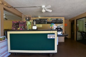 Un mostrador con un tablero de menú y un cartel que indica que el local está abierto.