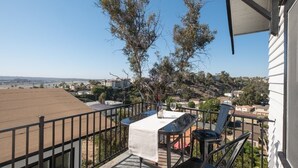 Un balcón con mesa y sillas, con vistas a una zona residencial y un paisaje distante.