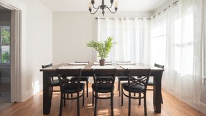 Un comedor con una mesa de madera, seis sillas, una lámpara de araña y una planta en maceta.
