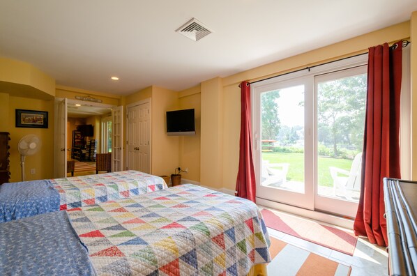 A hotel room with two beds, a TV, a sliding glass door to a patio, and a sign reading "LOFT APARTMENTS".