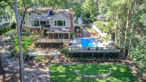 A house with a backyard deck, a swimming pool, and a fenced garden area. - Pool, lake, hot tub, fishing, fun-Lake Lanier GA. Newly renovated and open again (Gainesville)