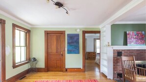 A spacious room with hardwood floors, a wooden door, and a vibrant striped rug.