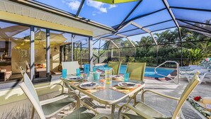 Un espace extérieur abrité où l’on peut prendre ses repas, avec une piscine en arrière-plan.