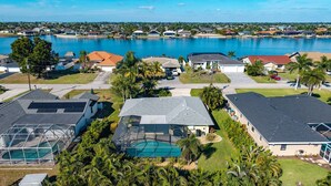 A residential area with houses, a swimming pool, and a large body of water in the background.