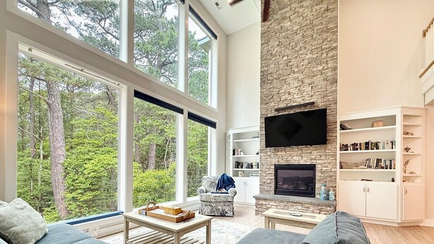 Una sala de estar moderna con chimenea de piedra, ventanas amplias y una estantería.