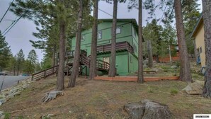 A green building with a staircase leading to the entrance, surrounded by trees. - SKI MOUNTAIN GETAWAY! AMAZING LOCATION FOR SKIING, HIKING AND SEEING LAKE TAHOE. (Stateline)