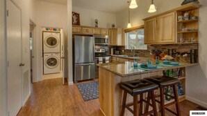 A kitchen with wooden cabinets, stainless steel appliances, and a central island with bar stools.