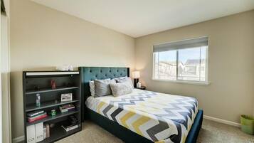 Une chambre à coucher avec un lit, une bibliothèque, une fenêtre et une vue sur les bâtiments à l’extérieur.